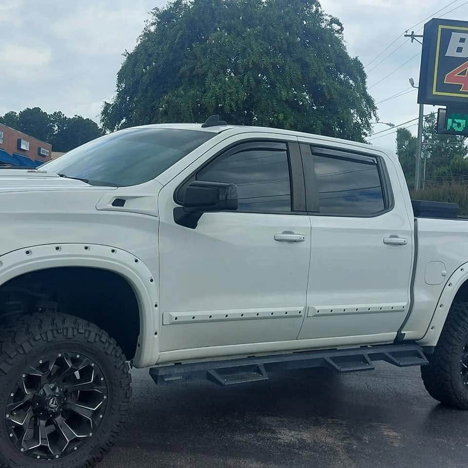 White lifted pickup truck with black wheels parked outdoors