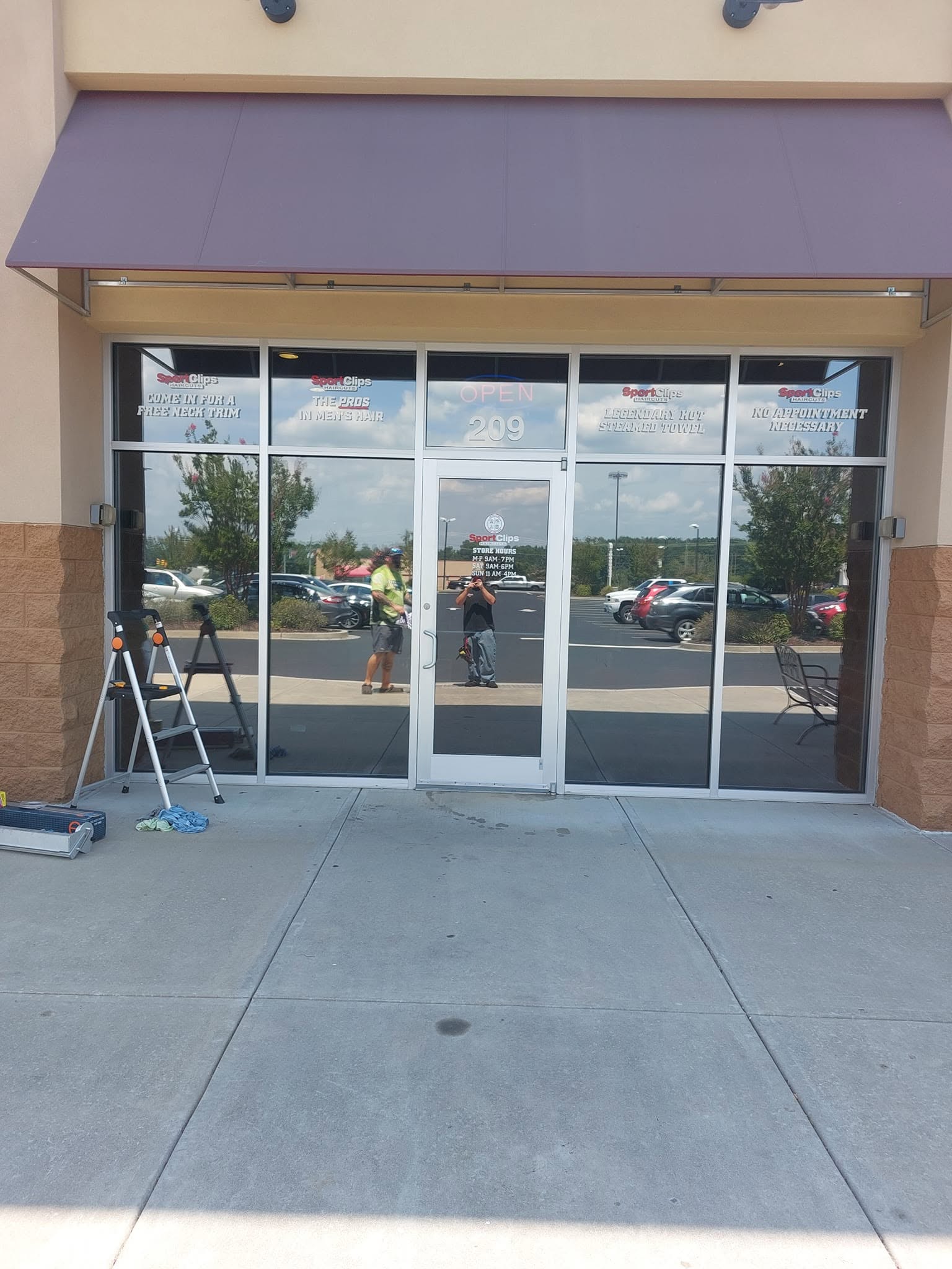 Sport Clips storefront with purple awning, glass doors, and ladder outside during renovation
