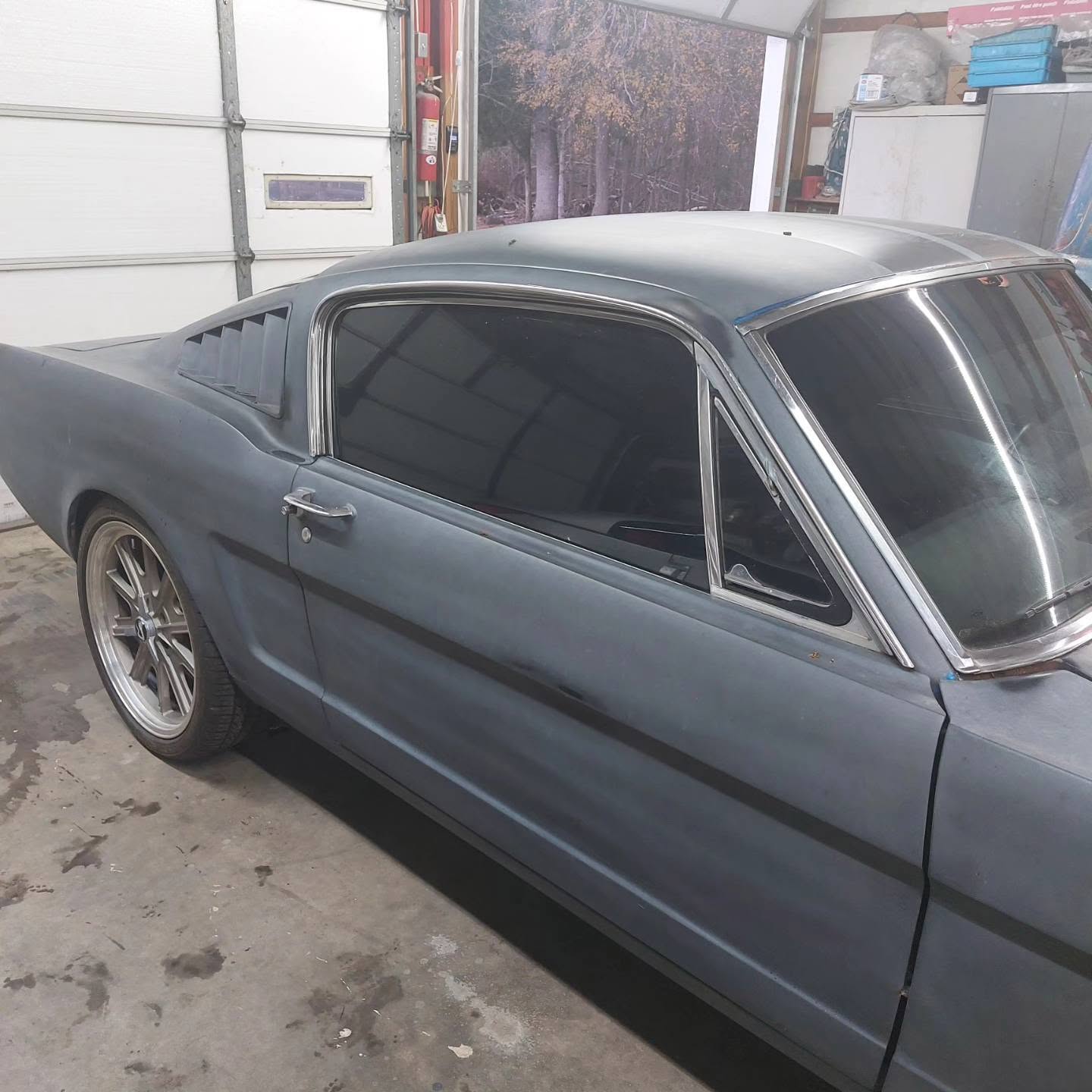 Gray vintage muscle car with custom wheels in garage bay