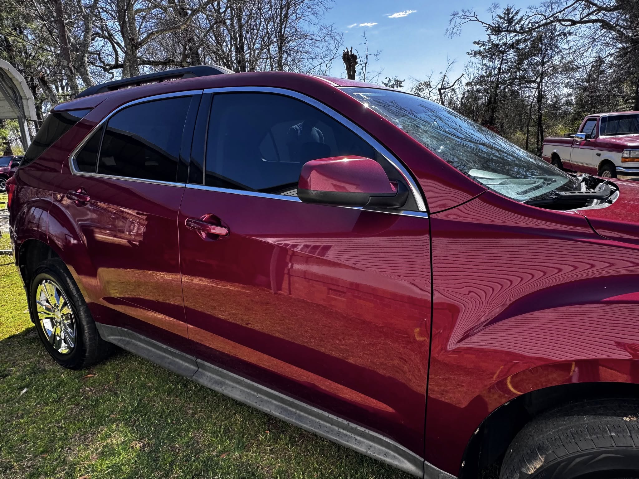 Burgundy SUV with tinted windows displayed at outdoor car show on grass