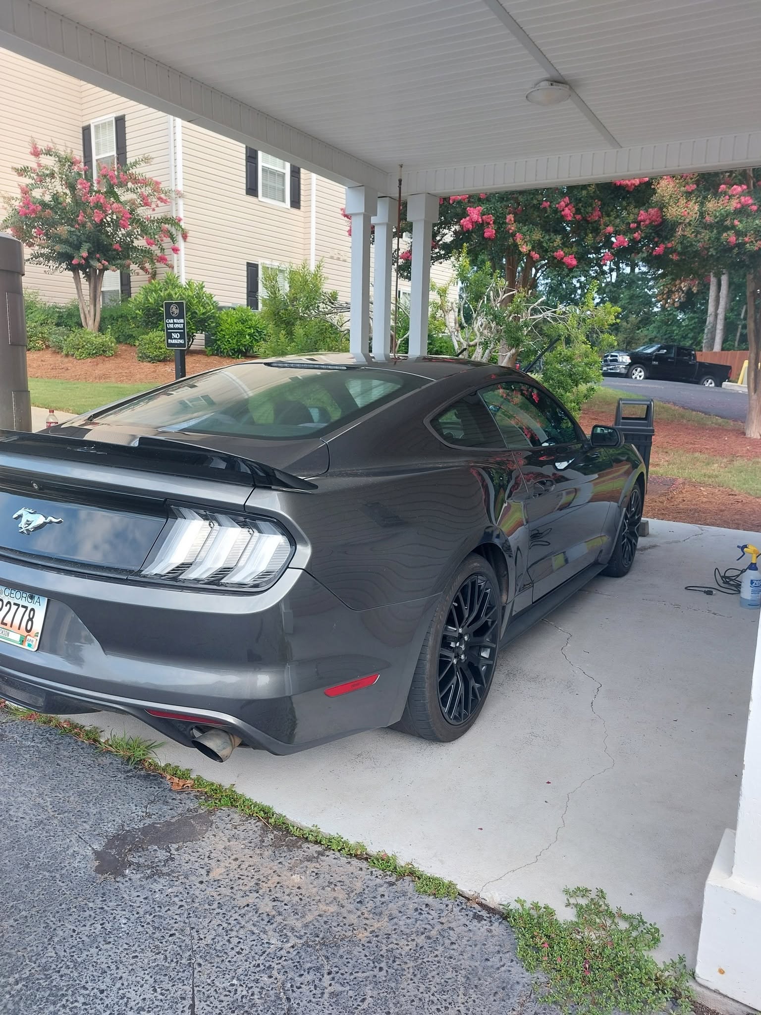 Dark gray Ford Mustang parked in driveway under covered carport